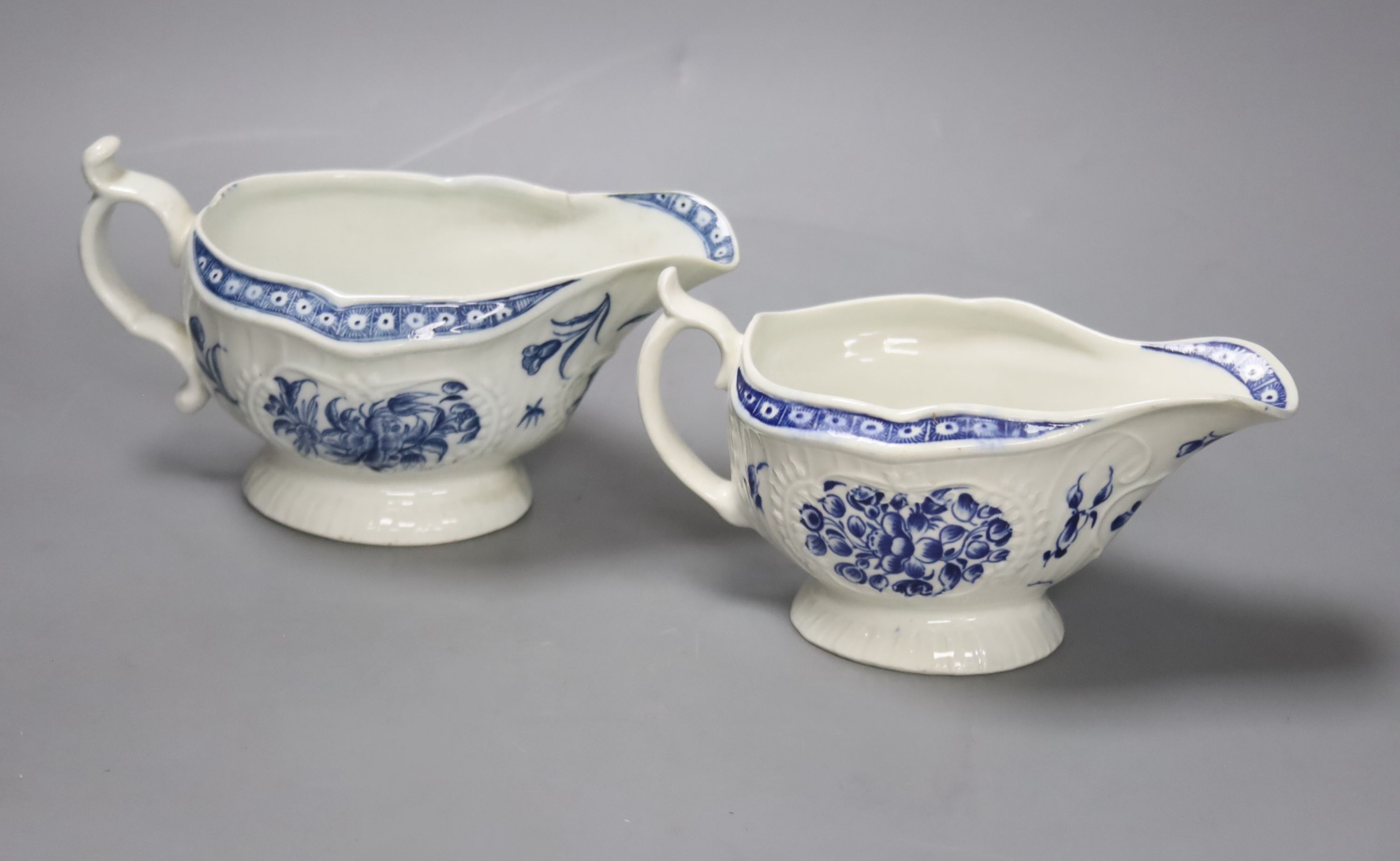Two Worcester strap fluted floral sauceboats, c.1770, with scratch cross mark and crescent mark and the other crescent mark, height 17cm